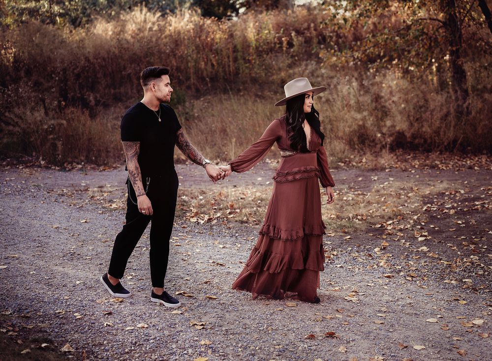 Young couple holding hands walking towards forest at Princes Island Park, Calgary, Alberta
