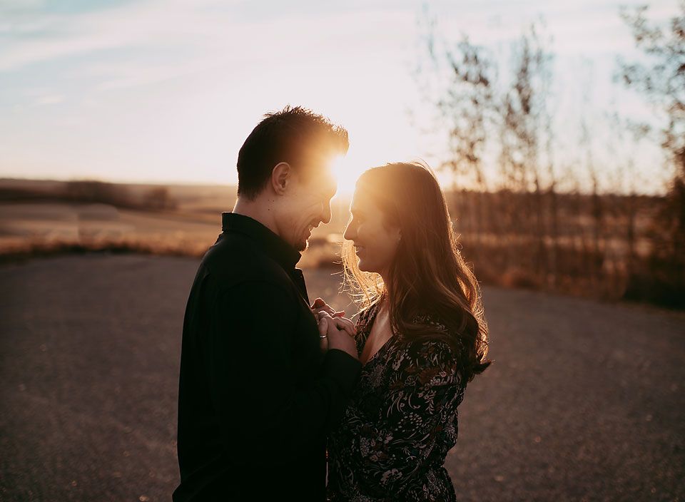 Young couple looking at each other with the sun setting between them in Airdrie, Alberta