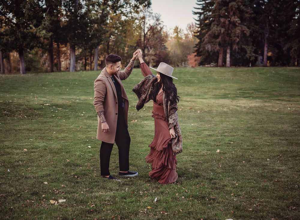 Young man twirling his girlfriend around on green grass at Princes Island Park, Calgary