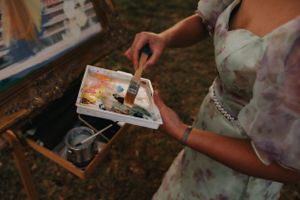 Artist working with watercolors to capture building details on canvas outdoors.