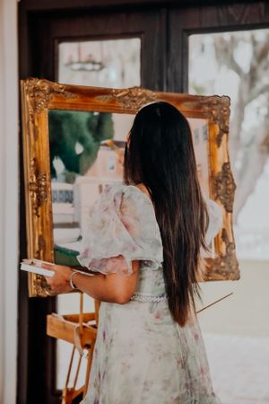 A floral dress is reflected in ornate gold-framed mirrors in an elegant interior space.