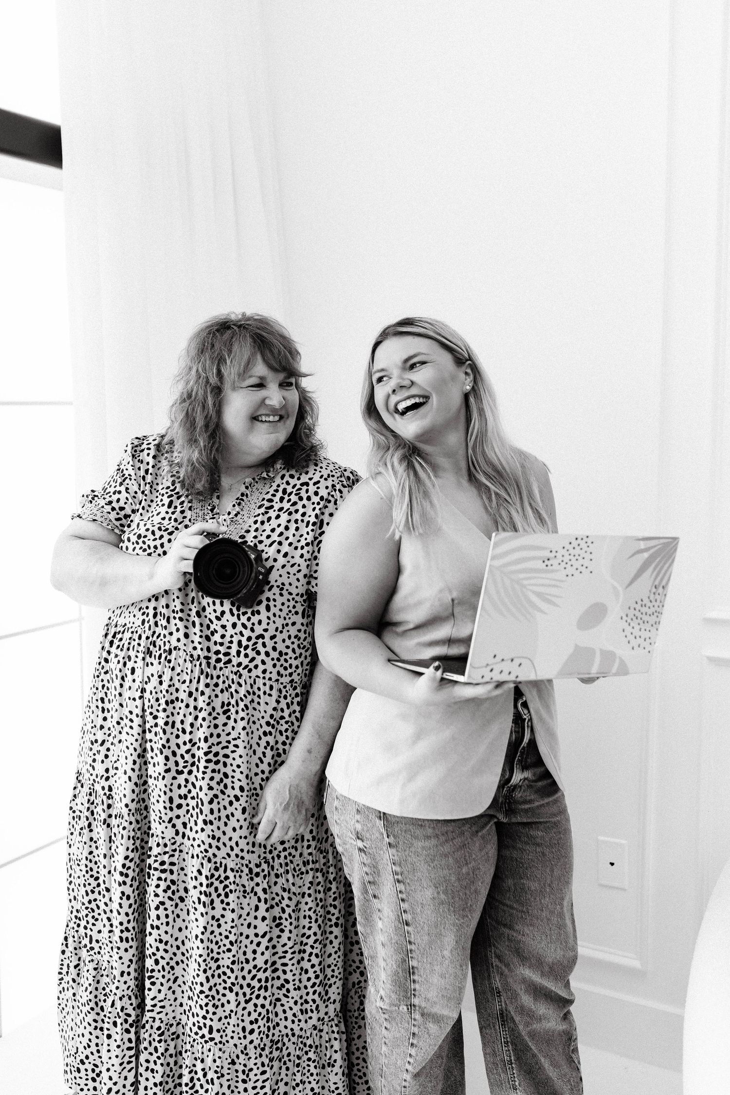 Two photographers share candid laughing moments during a studio session.