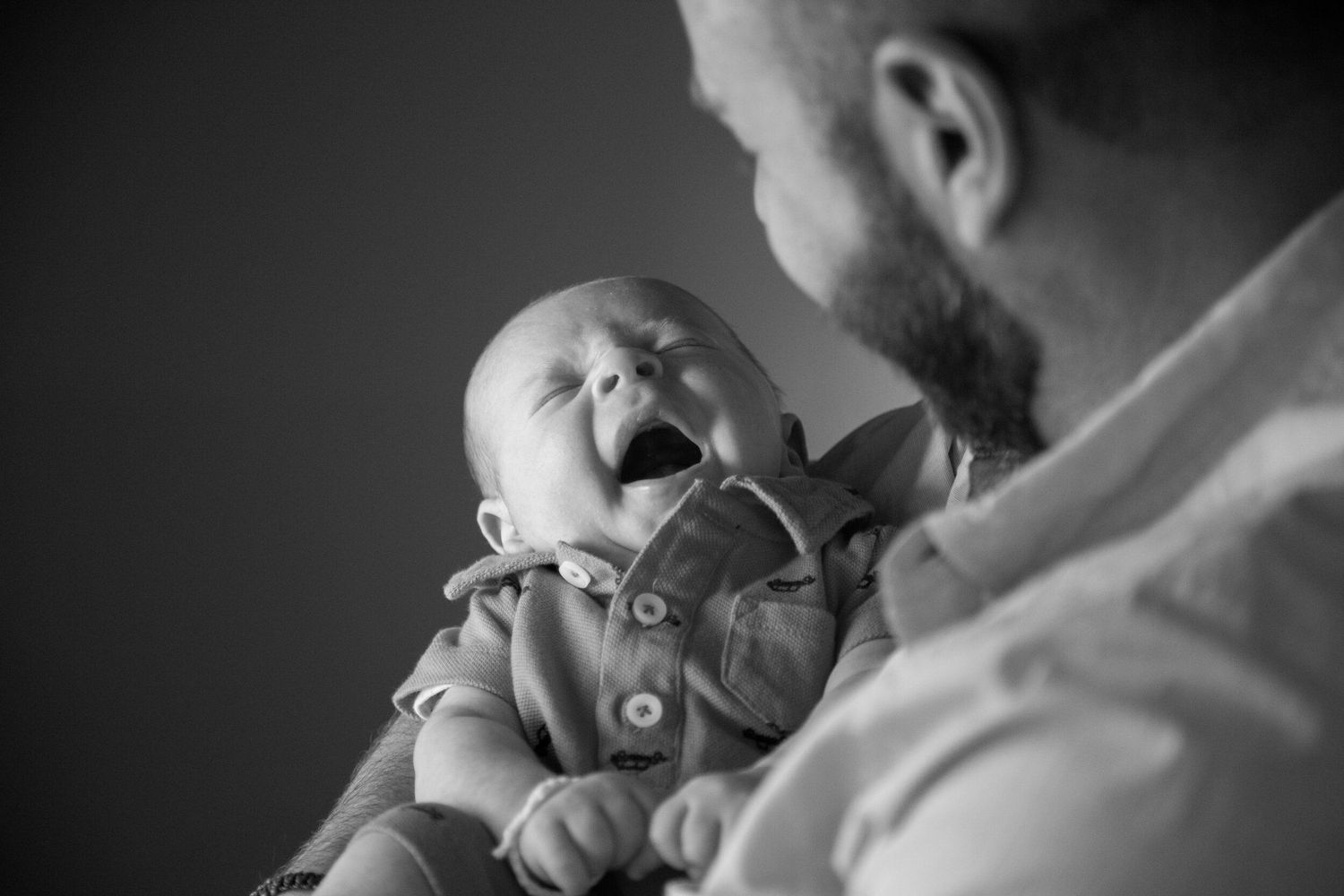 An emotional black and white portrait of a joyful baby with their caregiver.