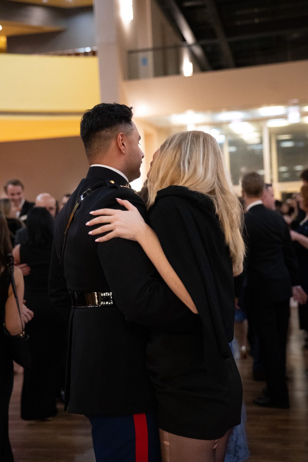 Marine in dress uniform slow dancing with a woman in a black dress at a formal military ball.