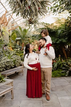 Romantic couple shares tender moments in a greenhouse conservatory filled with lush tropical plants and stone pathways In Wheaton Maryland