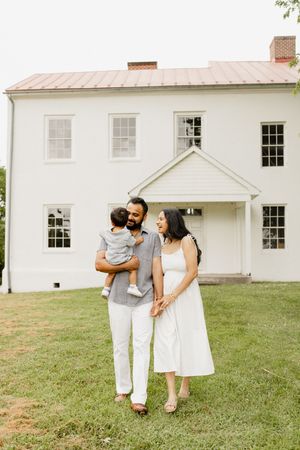 A couple shares romantic moments on a grassy lawn in front of a white colonial-style house in Frederick Maryland