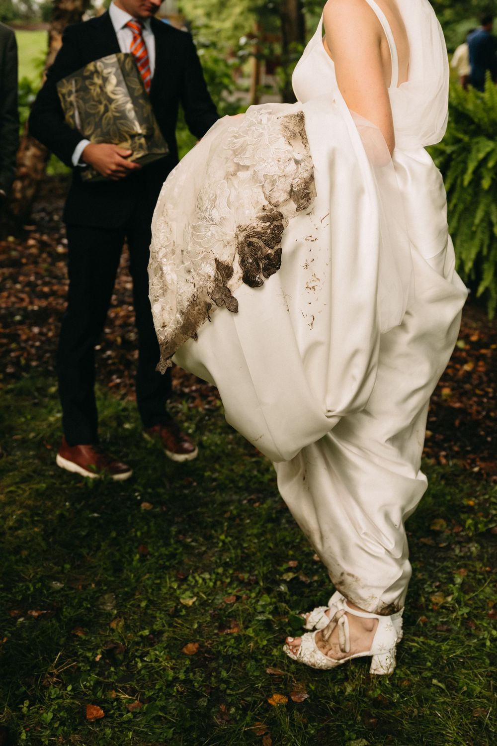 Close-up series showing muddy hem of white wedding dress dragging on grass in outdoor garden setting.