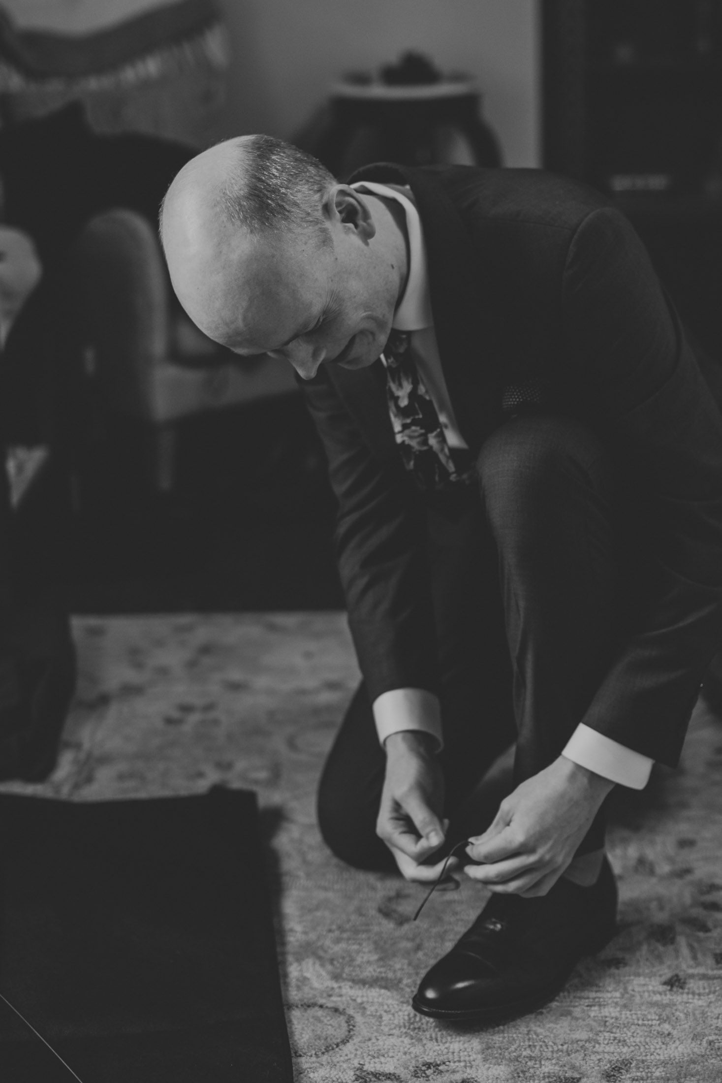 A series of black and white photos showing someone putting on dress shoes while getting ready.