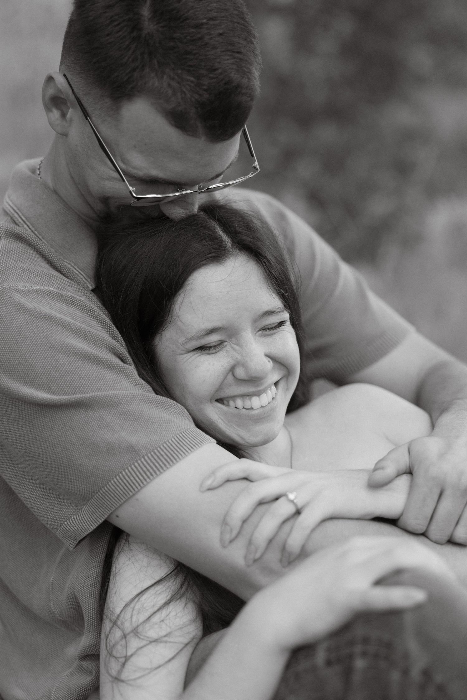 Black and white engagement photo of a couple hugging in a candid moment