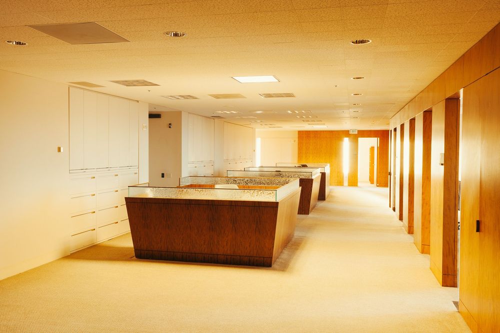 Modern office hallway with wooden reception desks and warm lighting.