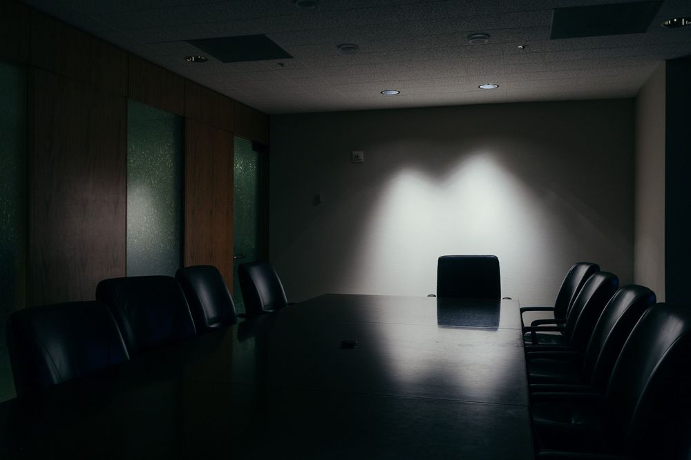 Dark conference room with black chairs and ambient lighting.