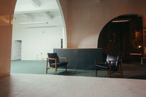 Empty industrial hallway with concrete floors and white walls lit by overhead lighting.