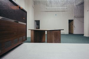 Long empty corridor with white walls and wooden paneling in an institutional building.