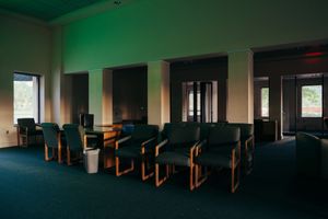 Dark green institutional room with rows of wooden furniture visible in low light.