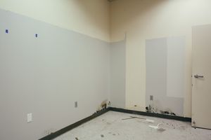 Empty room with white walls and exposed electrical outlets during renovation.