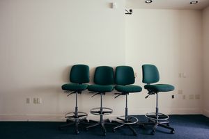 Institutional room with teal office chairs arranged against a white wall.