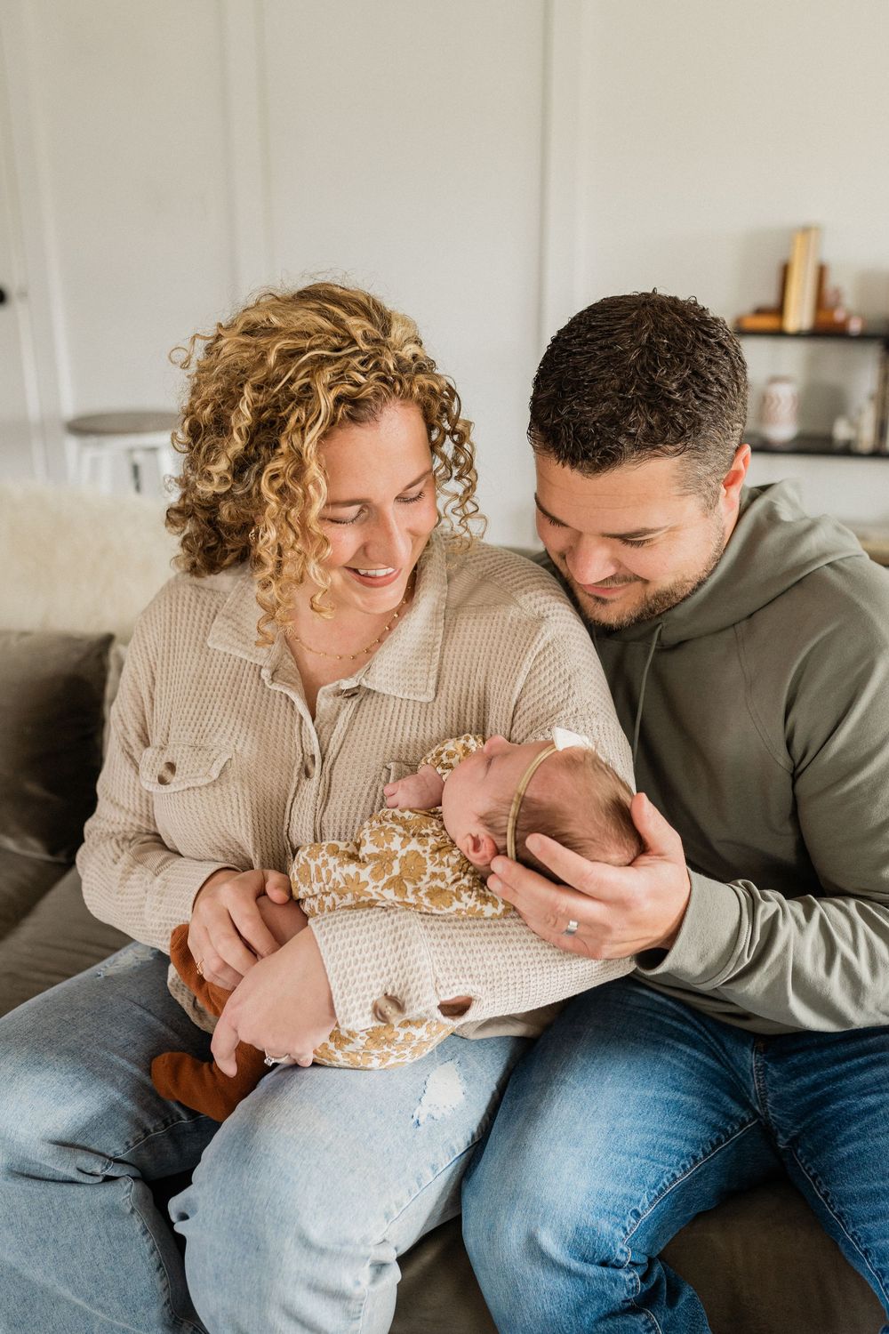 A couple snuggles with their newborn baby on a couch in a series of tender moments.