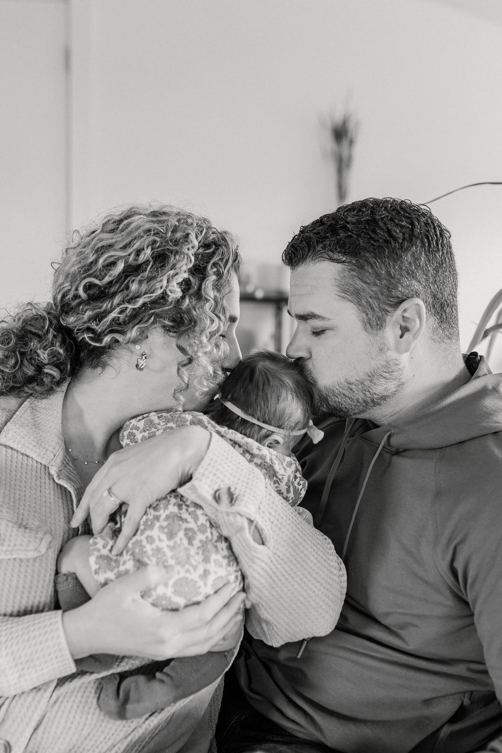 Black and white photos capture tender moments between parents and their newborn baby.