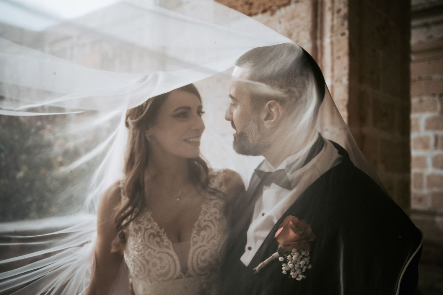 Intimate wedding portrait with flowing veil creating a dreamy effect.
