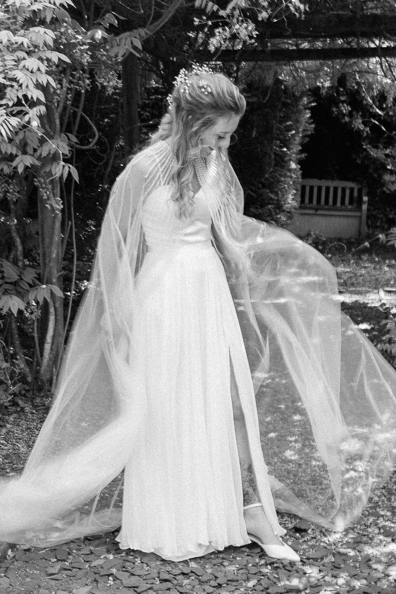 Series of black and white photos showing a flowing white dress and veil moving ethereally in an outdoor garden setting at tipis riley green