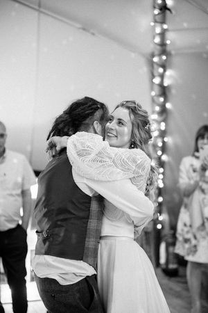 A couple embraces on the dance floor at a wedding reception with string lights glowing in the background at the tipis riley green, lancs