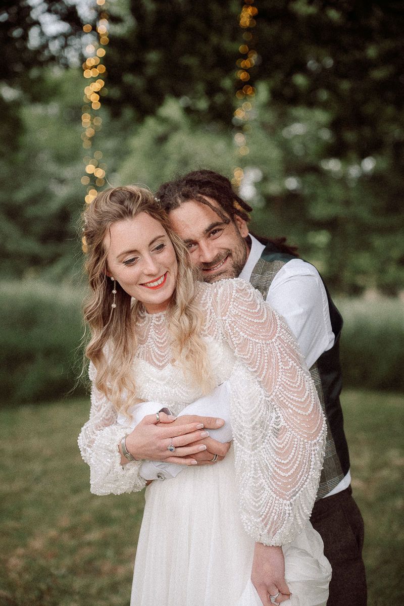 A romantic outdoor wedding portrait with twinkle lights showing a couple embracing in a natural setting at the tipis riley green, lancs