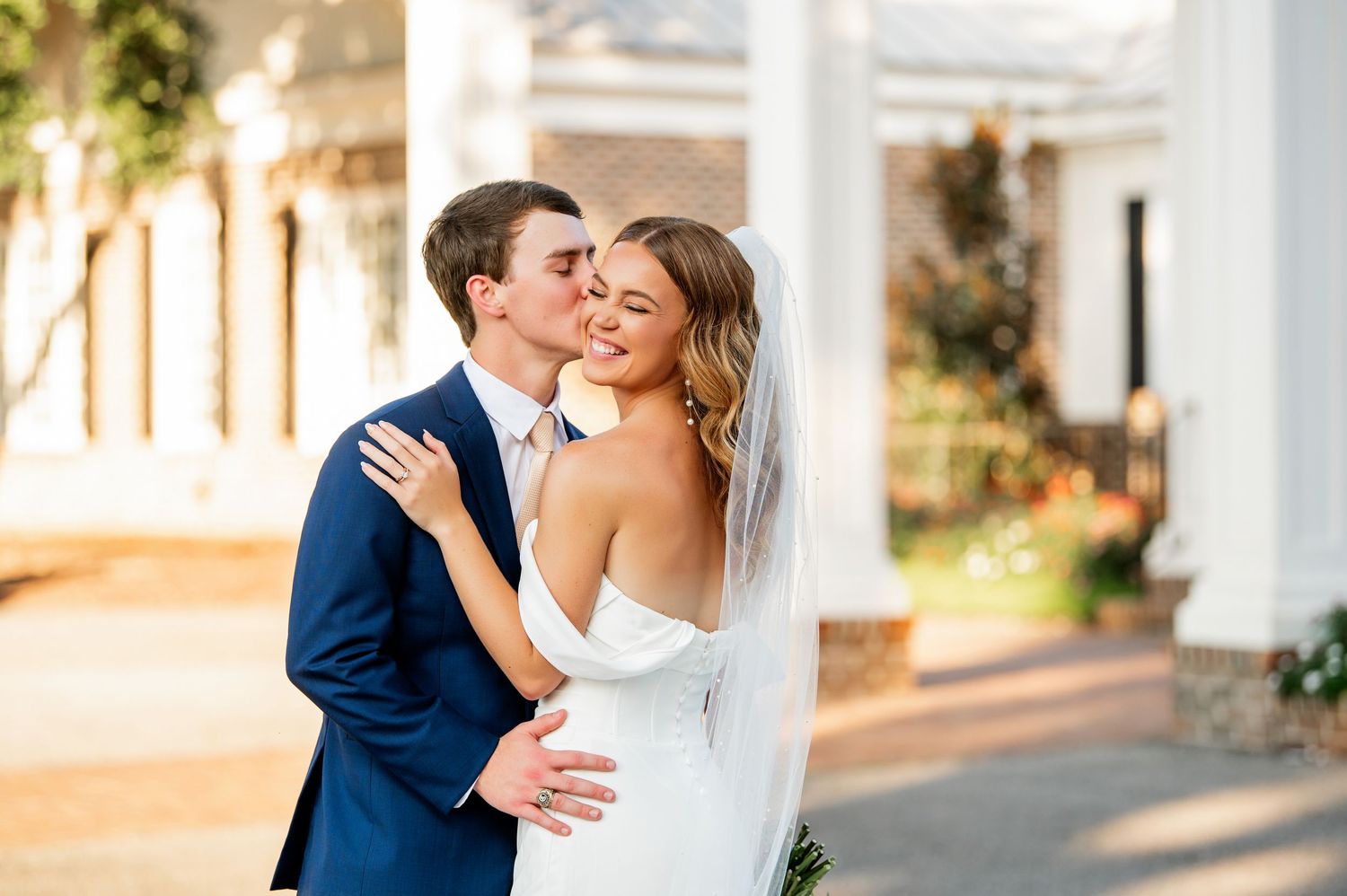 Elegant outdoor wedding portraits captured against white colonial architecture.
