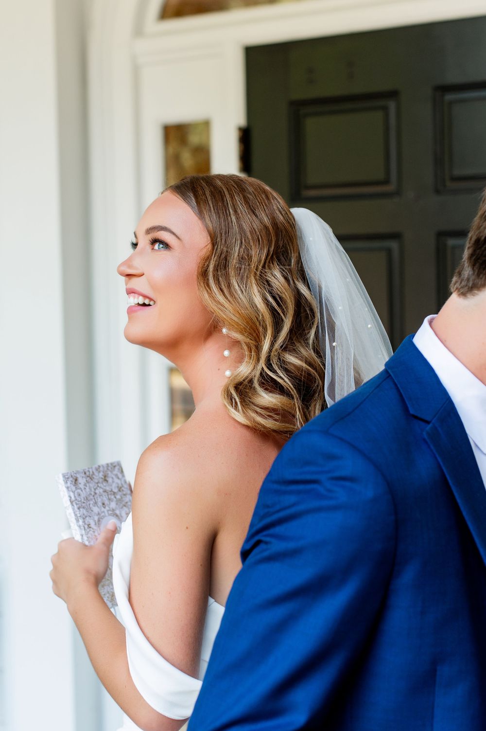 A couple laughs while standing back to back during their first look wedding moment.