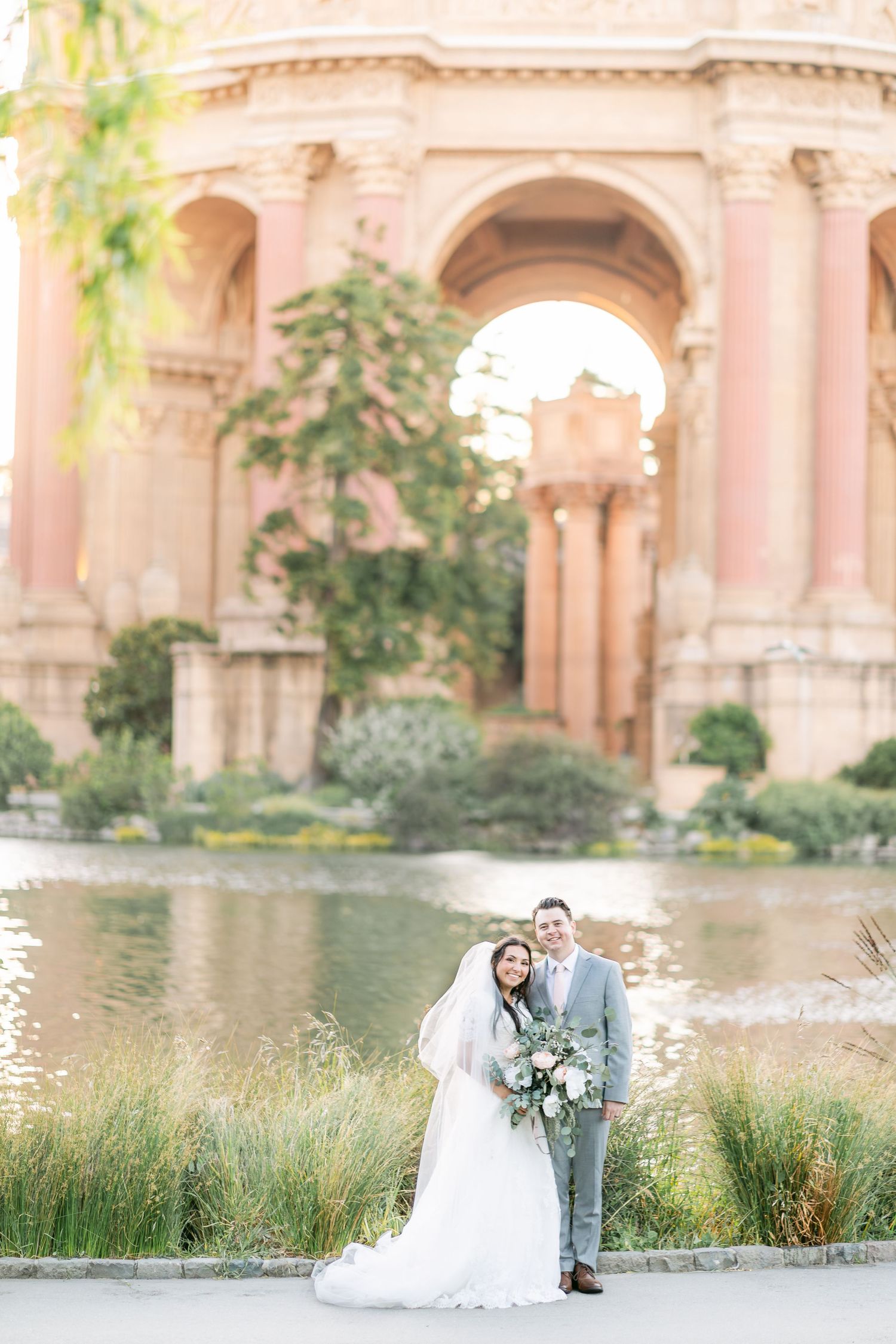Elegant wedding couple poses in front of the Palace of Fine Arts in San Francisco during golden hour.