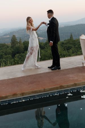 Couple sharing a romantic moment on a terrace overlooking mountain views at sunset.