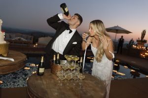 Wedding celebration with champagne toast on outdoor terrace at twilight.