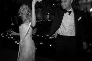 Black and white photo of dancing and celebration at nighttime wedding reception.