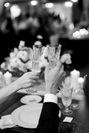 Hands raising champagne glasses in a toast at elegant dinner.