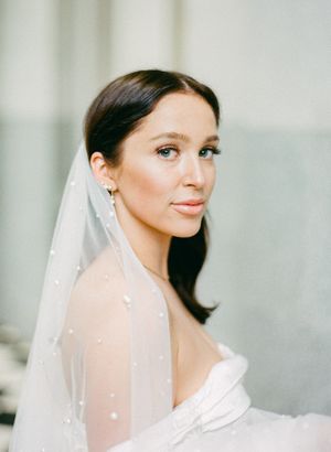 Close up portrait of a bride wearing a sheer veil and elegant white wedding gown.