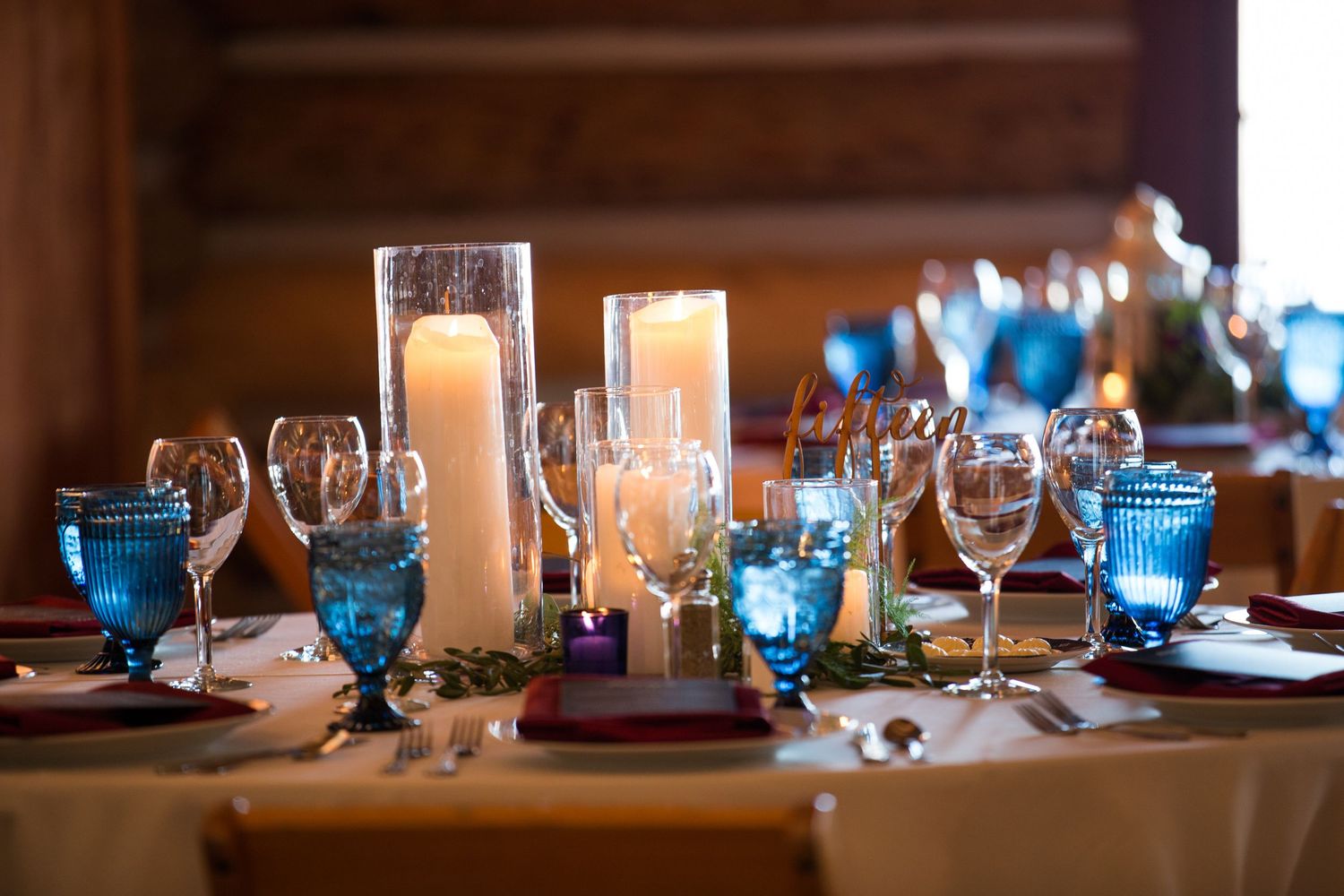 Elegant table setting with blue glassware and candlelight creates a romantic dining atmosphere at dusk.