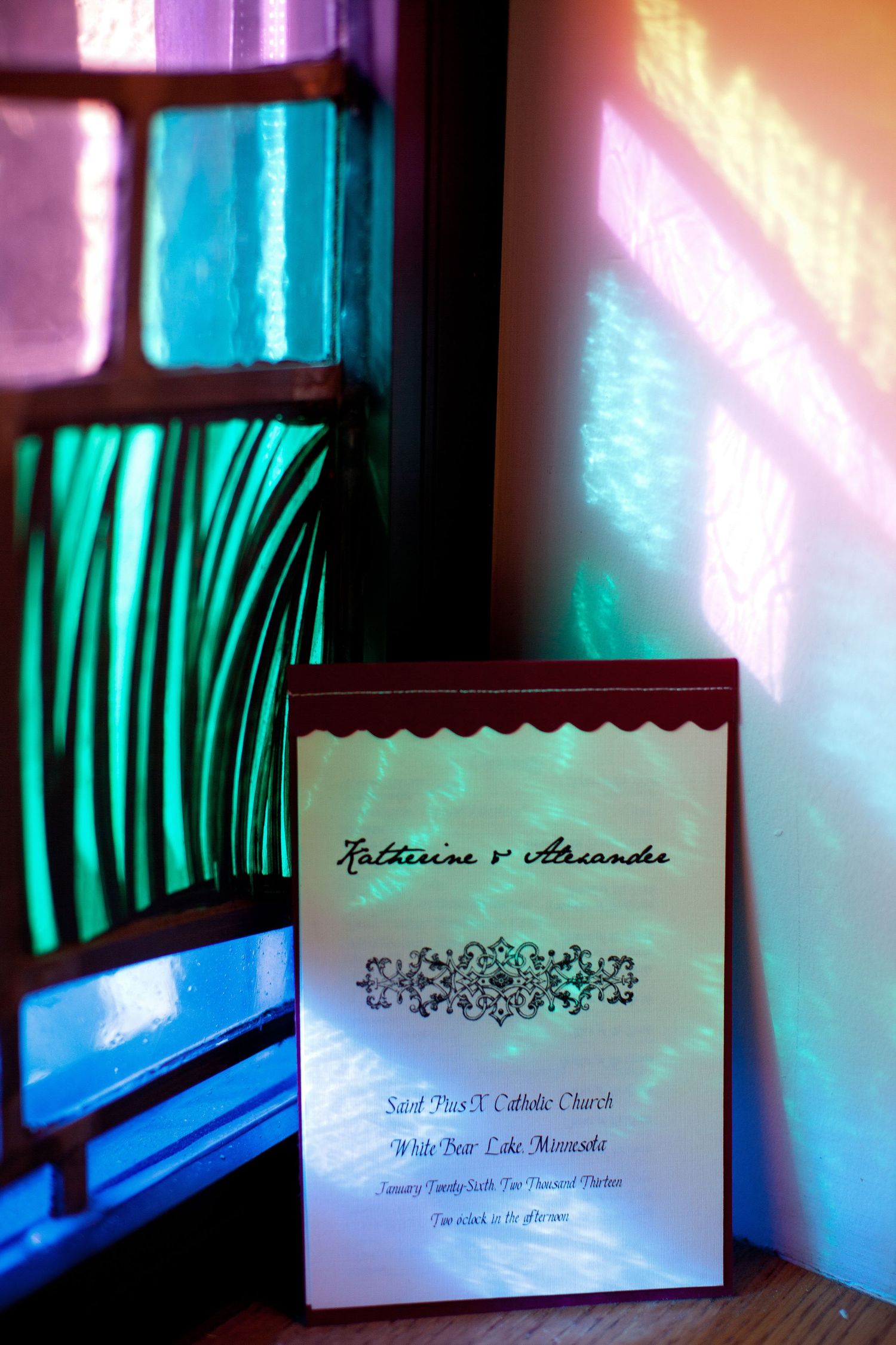 Wedding invitation cards with elegant calligraphy and floral designs displayed against a blue-green background.