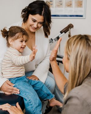 Medical staff interacting with a young patient and caregiver during a consultation in a bright clinic setting.