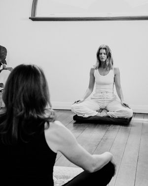 People practicing meditation and mindfulness exercises on a wooden floor in a minimalist studio space.