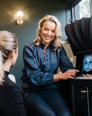 Professional esthetician performing facial treatments in a modern spa setting with dark walls and ambient lighting.