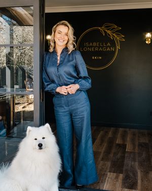 A fluffy white Samoyed dog sits in an elegant spa reception area with dark walls and wood flooring.