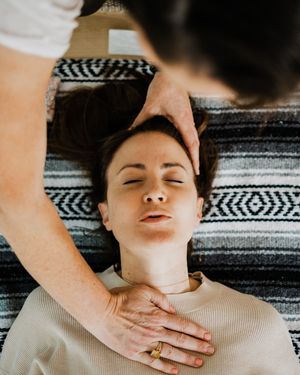 Person receiving a relaxing head and neck massage while lying on a geometric patterned blanket.