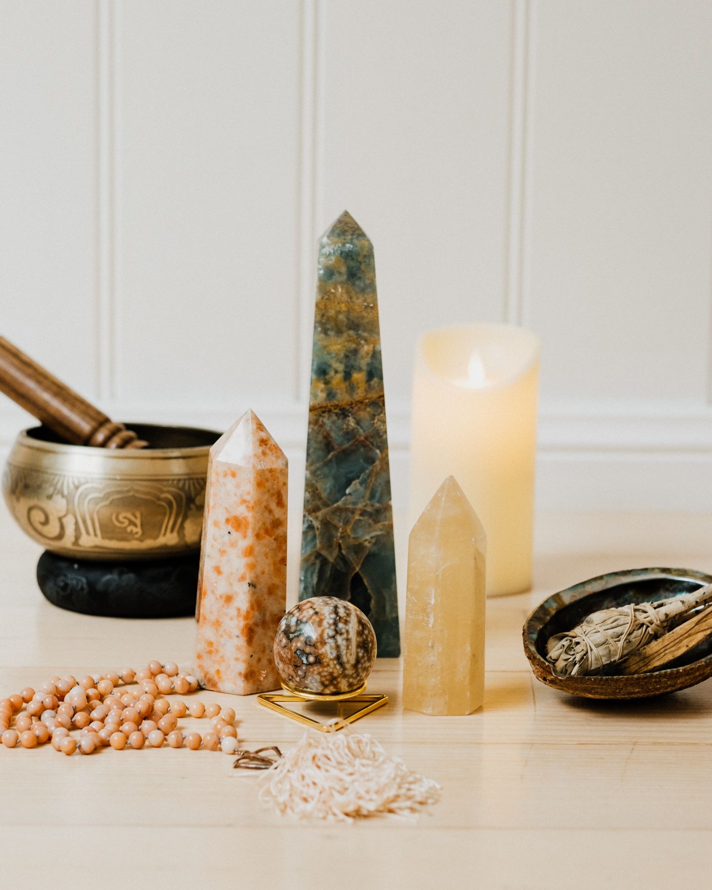 Spiritual healing crystals, singing bowls, and lit candles arranged with pink Himalayan salt on a white surface.