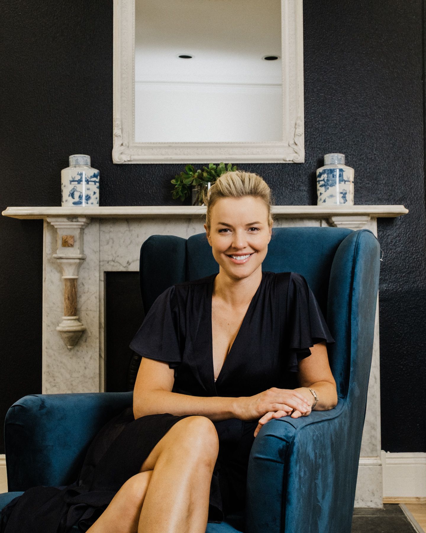 Professional seated in a navy blue armchair in a modern office setting with white walls and decor.