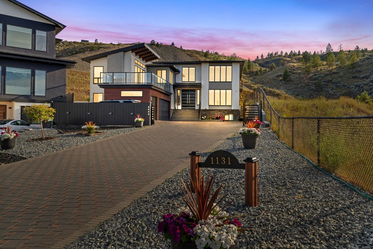 Exterior view of modern manufactured homes with gravel landscaping and trees in the background under blue sky.
