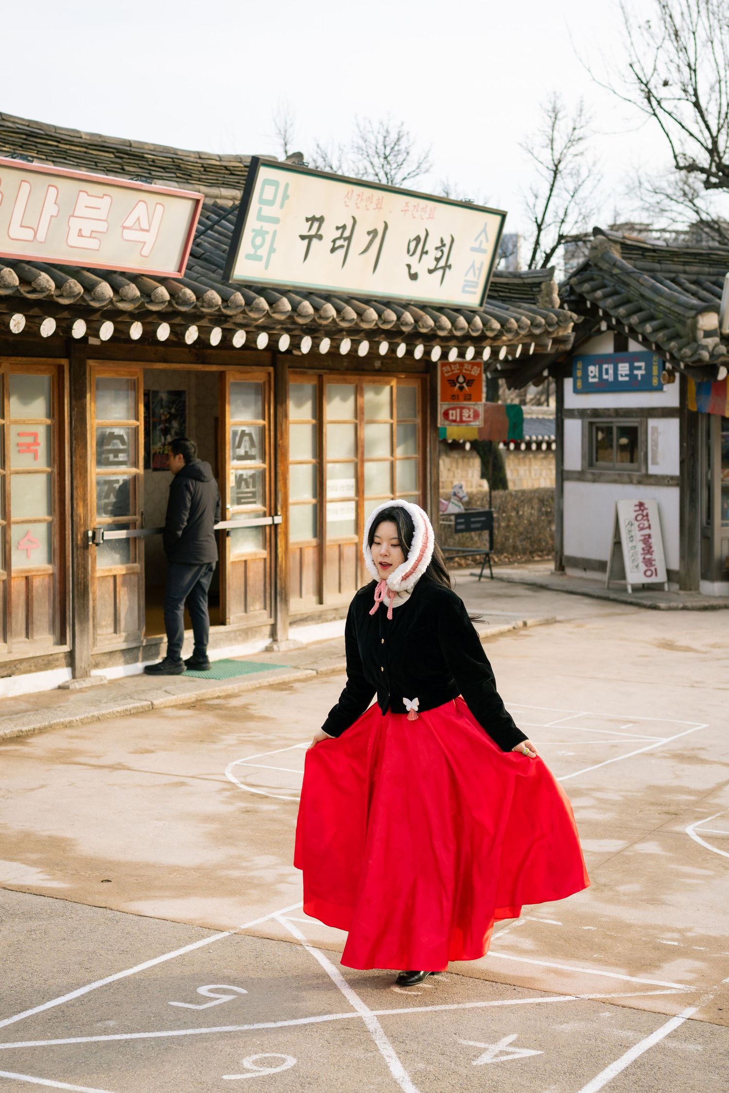A series of photos showing someone in traditional Korean hanbok with a vibrant red skirt at a traditional courtyard setting.