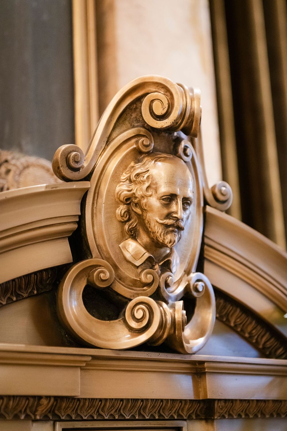 Ornate architectural detail showing carved baroque scrollwork and decorative relief sculpture in beige stone in the Bellevue Hotel
