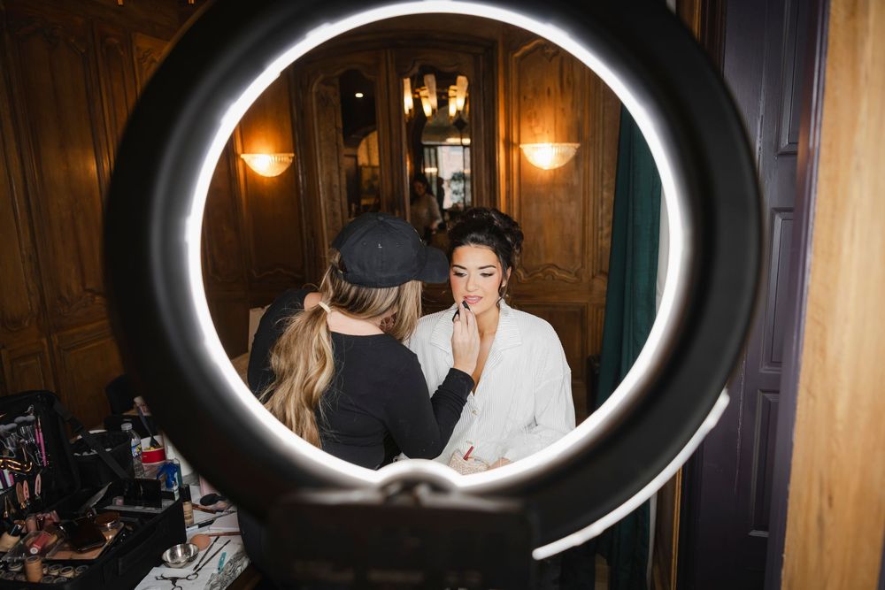 A candid moment photographed through the artist's ring light of the bride getting her makeup done.