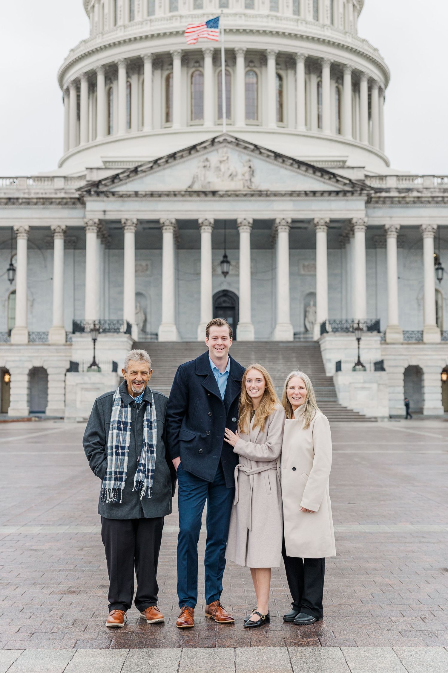 A small group stands together on the steps of the United States Capitol building in Washington DC.