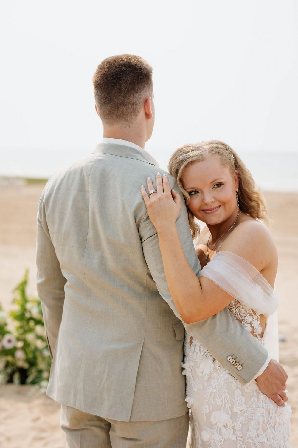 A bride and groom share intimate moments during their beach wedding photoshoot in light, airy conditions.