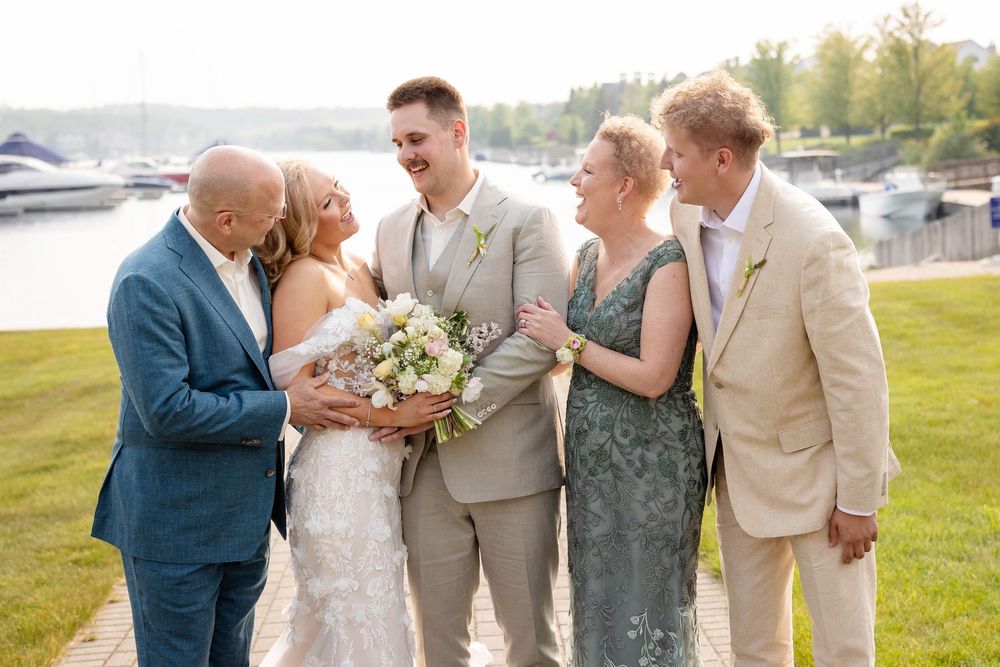 Wedding party celebrates outdoors with champagne spraying in a joyful moment on a sunny day.